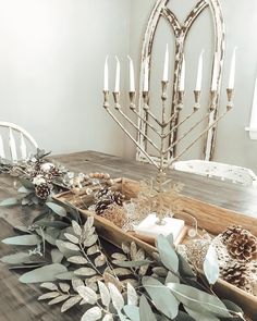 a wooden table topped with candles and greenery