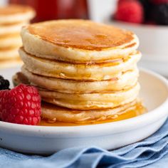 a stack of pancakes on a plate with berries and syrup