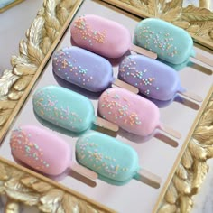 there are four pops with sprinkles on them in a gold frame next to a mirror