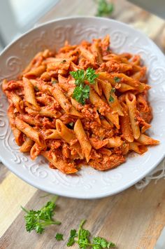 pasta with meat sauce and parsley in a white bowl on a wooden table top