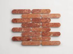 a group of red marble bricks arranged in a row on a white surface with one brick missing