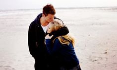 a man and woman kissing on the beach