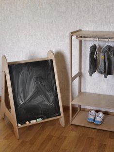 a chalkboard and two wooden shelves with shoes on the floor in front of it