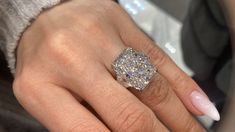 a woman's hand with a diamond ring on top of her finger and white nails