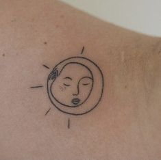 a small tattoo on the back of a woman's shoulder with a sun and moon