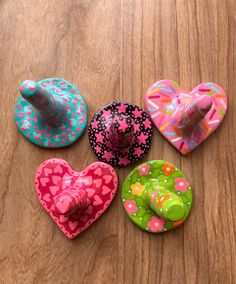 four heart shaped hair clips sitting on top of a wooden table next to each other