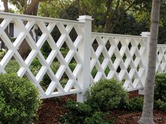 a white picket fence surrounded by bushes and trees