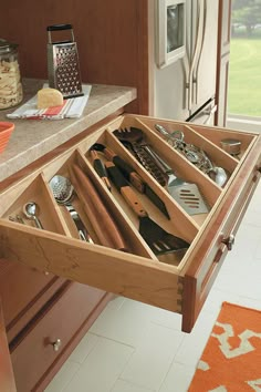 an open drawer with utensils and spoons in it on a counter top