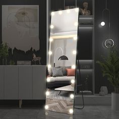 a large mirror with lights on it in the middle of a room next to a couch