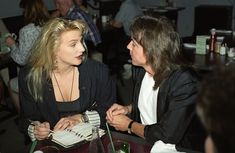 two women sitting next to each other at a table in a restaurant, one talking