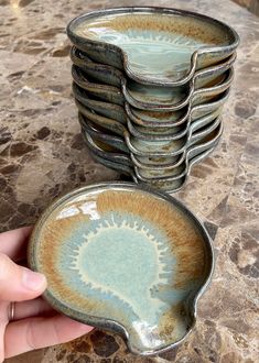 a hand holding a stack of plates on top of a table