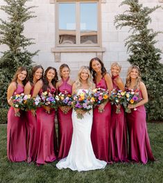 a group of women standing next to each other in front of a building holding bouquets