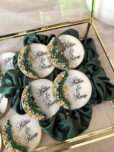 some white and green decorated cookies in a glass box with gold trimmings on them