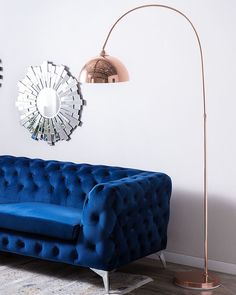 a living room with a blue couch and two mirrors on the wall above it, along with a gold floor lamp