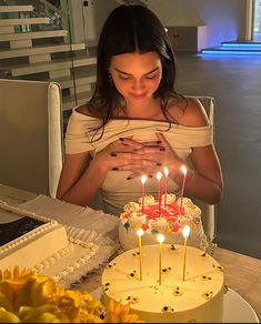 a woman sitting in front of a cake with lit candles