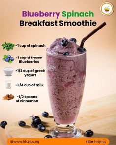 the blueberry spinach breakfast smoothie is in a tall glass with a straw