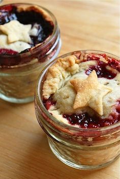 two small jars filled with food on top of a wooden table