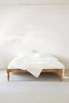 a bed with white sheets and pillows on top of it in front of a wall