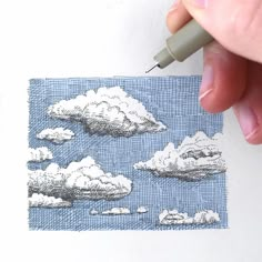 a person is drawing clouds on paper with a pen and inking them into small squares