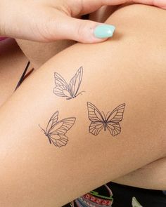 a woman's arm with three butterflies drawn on the back of her leg and one is