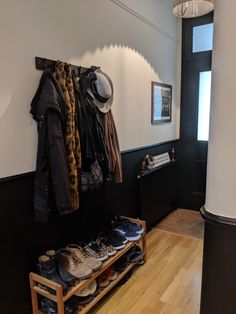 shoes and hats are hanging on the wall next to a coat rack in a room