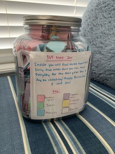 a jar filled with lots of different items on top of a blue table cloth next to a window