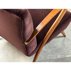 a brown chair sitting on top of a floor next to a wooden armrests