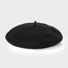 a black hat is sitting on a white surface and it's been made out of wool