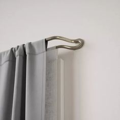 an open curtain with a metal handle hanging from it's side, in front of a white wall