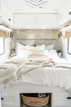 a white bed sitting in the middle of a bedroom next to a basket filled with pillows