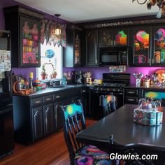 a kitchen with black cabinets and colorful decorations on the walls, along with a dining room table