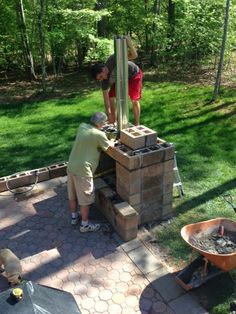 two men are building a brick fire pit