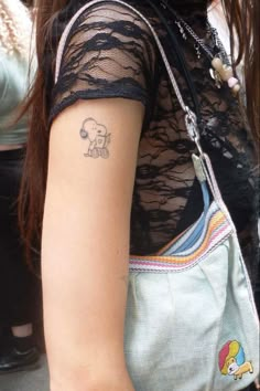 a woman with a small elephant tattoo on her left arm, holding onto a purse