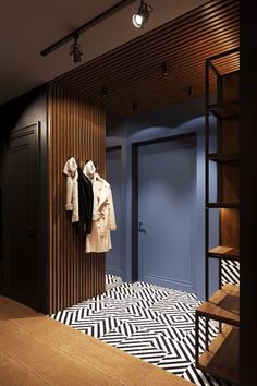 an open closet with clothes hanging on the wall and black and white patterned flooring