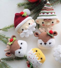 crocheted christmas ornaments are arranged on a white surface with pine branches and red berries