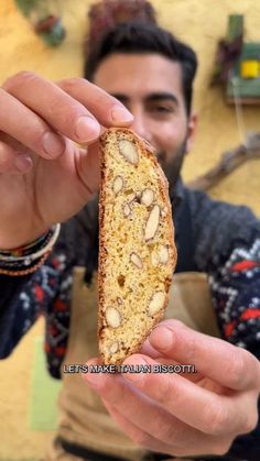 a man holding up a piece of bread with nuts on it