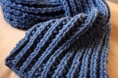 a blue knitted scarf laying on top of a couch