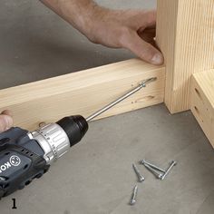 a man using a drill to attach screws on the side of a wooden frame