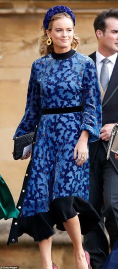 a woman in a blue dress is walking next to a man