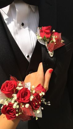 a person in a tuxedo with red roses and baby's breath flowers