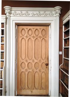 a wooden door in front of a bookshelf