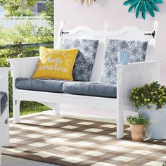 a white bench sitting on top of a checkered rug next to a potted plant