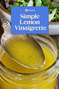 a glass jar filled with lemon vinaigrete next to a bowl of salad