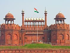 an old brick building with two towers and a flag on top is in the foreground