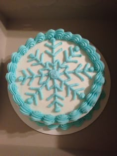 a white and blue frosted cake in a box with snowflakes on it