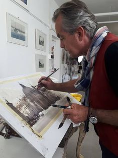 an older man is painting in his studio