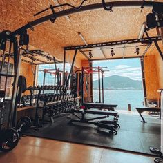 there are many gym equipment in the room by the water's edge, and one is empty