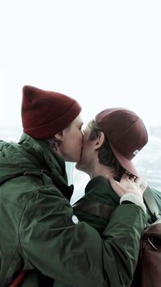 two people kissing each other in front of the ocean