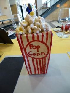 a popcorn bucket filled with white and red candy corn sitting on top of a table