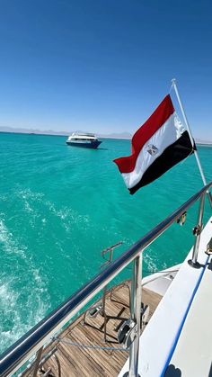 the flag of egypt is flying on top of a boat in the blue water with another boat behind it